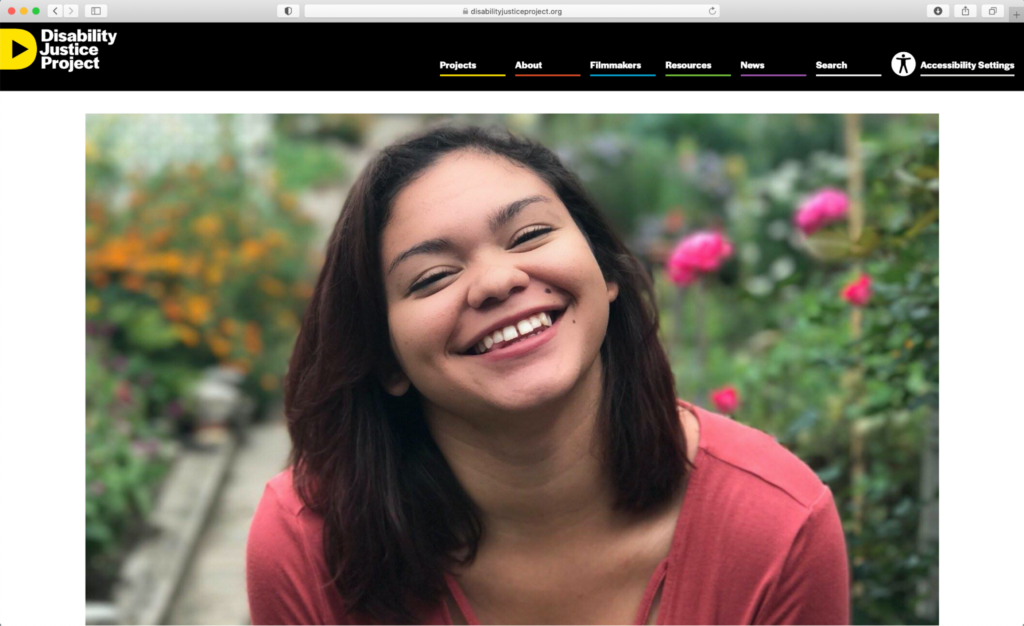 A news story on the Disability Justice's Project: "Invisible No More." The story features an image of a young biracial woman smiling into the camera. She is posing in front of a blurred background of flowers.