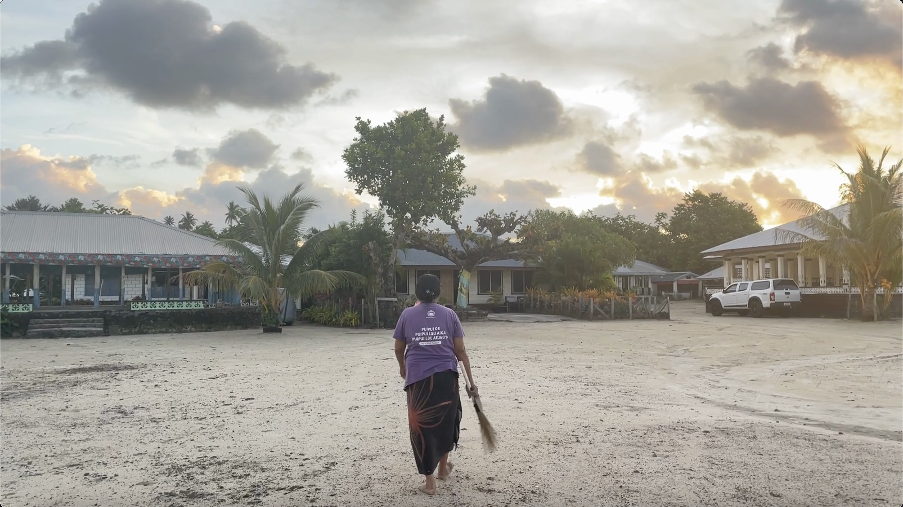 A woman walks across a sandy clearing.