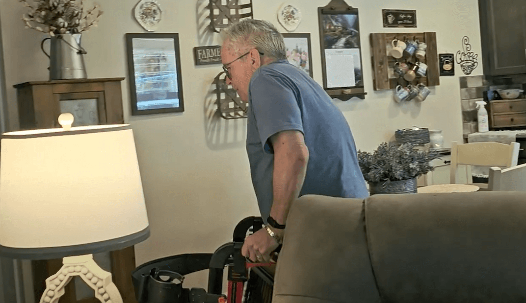 Larry Landrie uses his walker to navigate his living room.