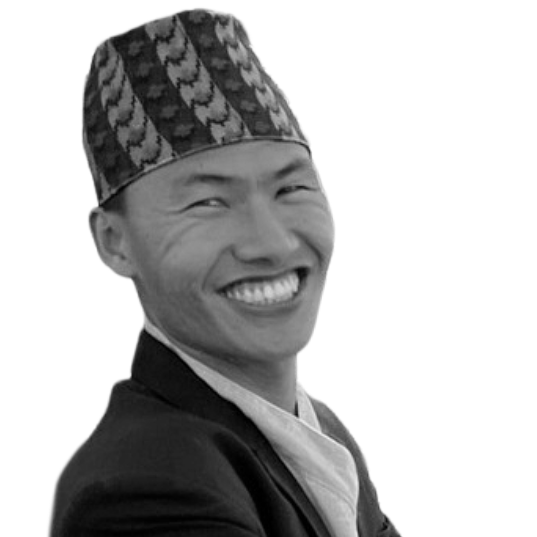 Urgyen Namdul smiles into the camera. He is a young Nepali man wearing a suit and traditional hat.