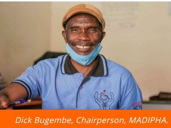 Dick Bugembe smiling at the camera, wearing a surgical mask down on his chin.