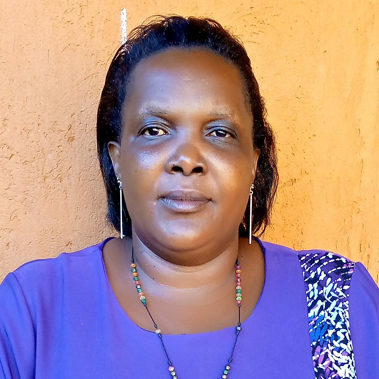 Christine Oliver Dhikusooka stands in front of building outside.