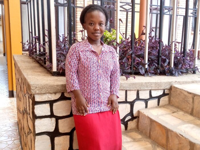 Marie Appoline Bumbtubwimana stands in front of a stone steps.