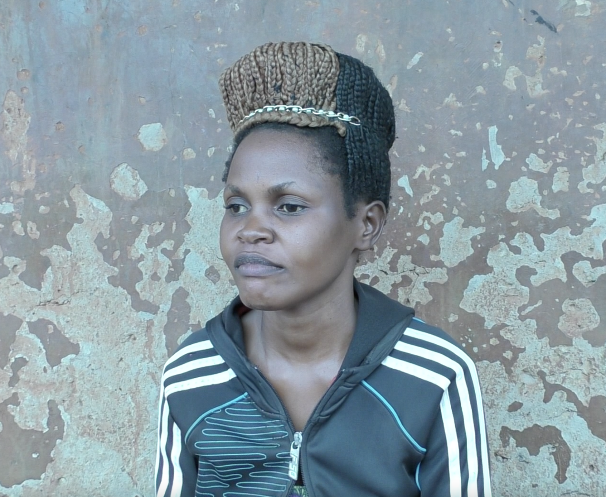 Esther Nandego stands in front of a cement wall.