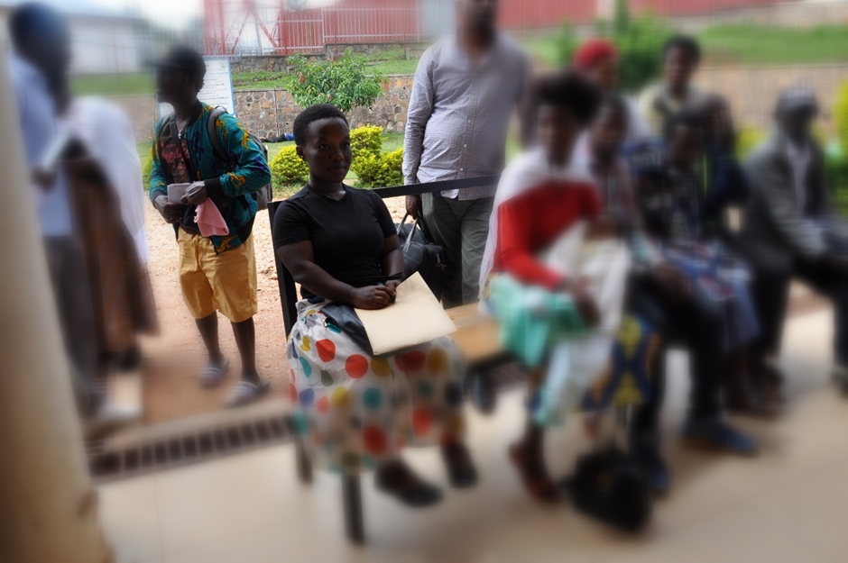 Appoline Buntubwimana sits on a bench in the reception area of a hospital.