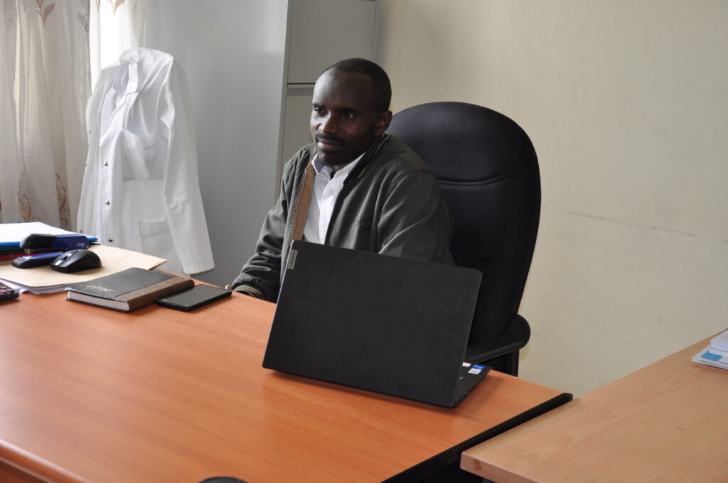 Leonidas Batamugira sits at a large wooden desk.