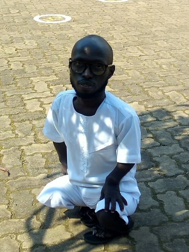 Theodole Niyigaba stands in the shade of a tree, looking at the camera.