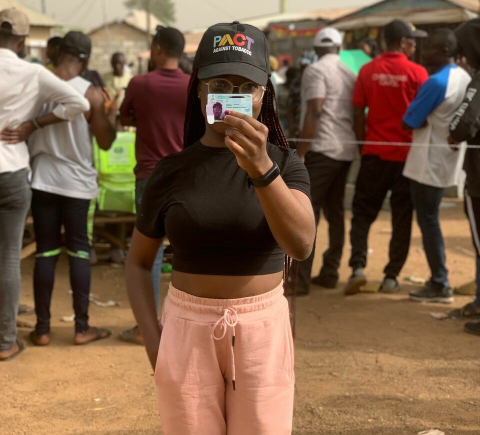 Oyewole holds up her permanent voters card in front of her polling station.