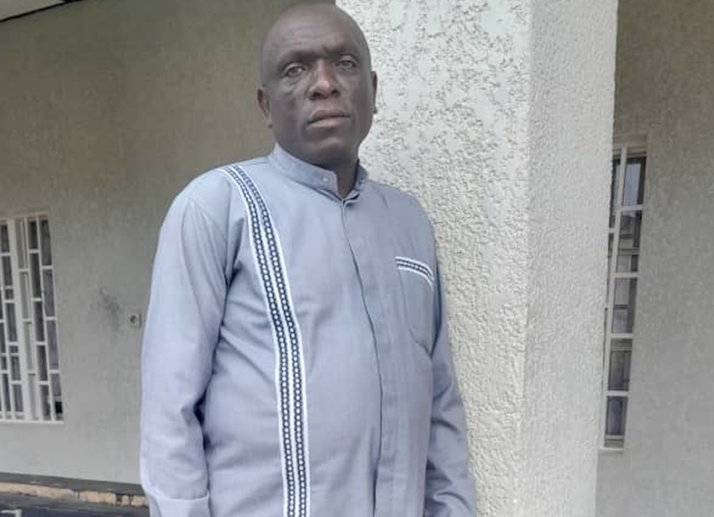 Emmanuel Nsengimana stands outside a building looking to camera.