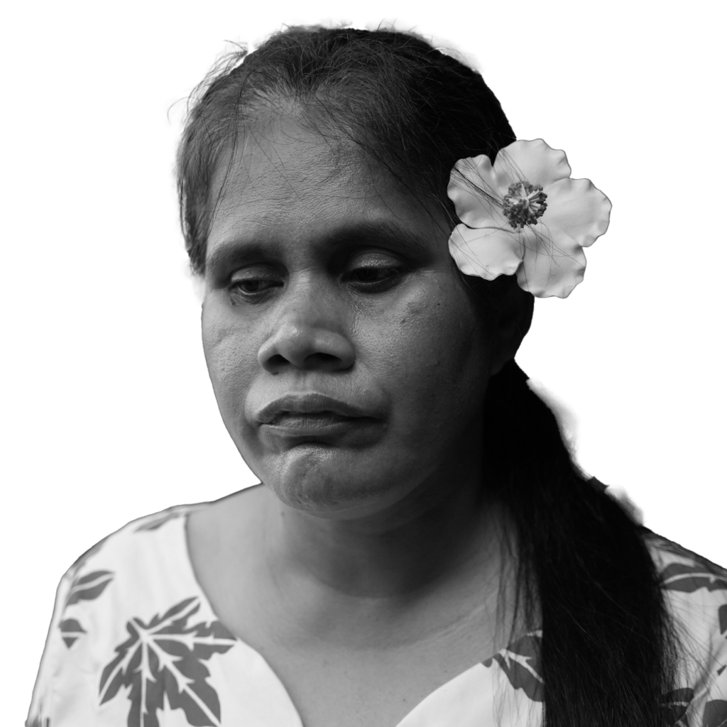 Faaolo Utumapu-Utailesolo stands in front of flowers with a contemplative look on her face.