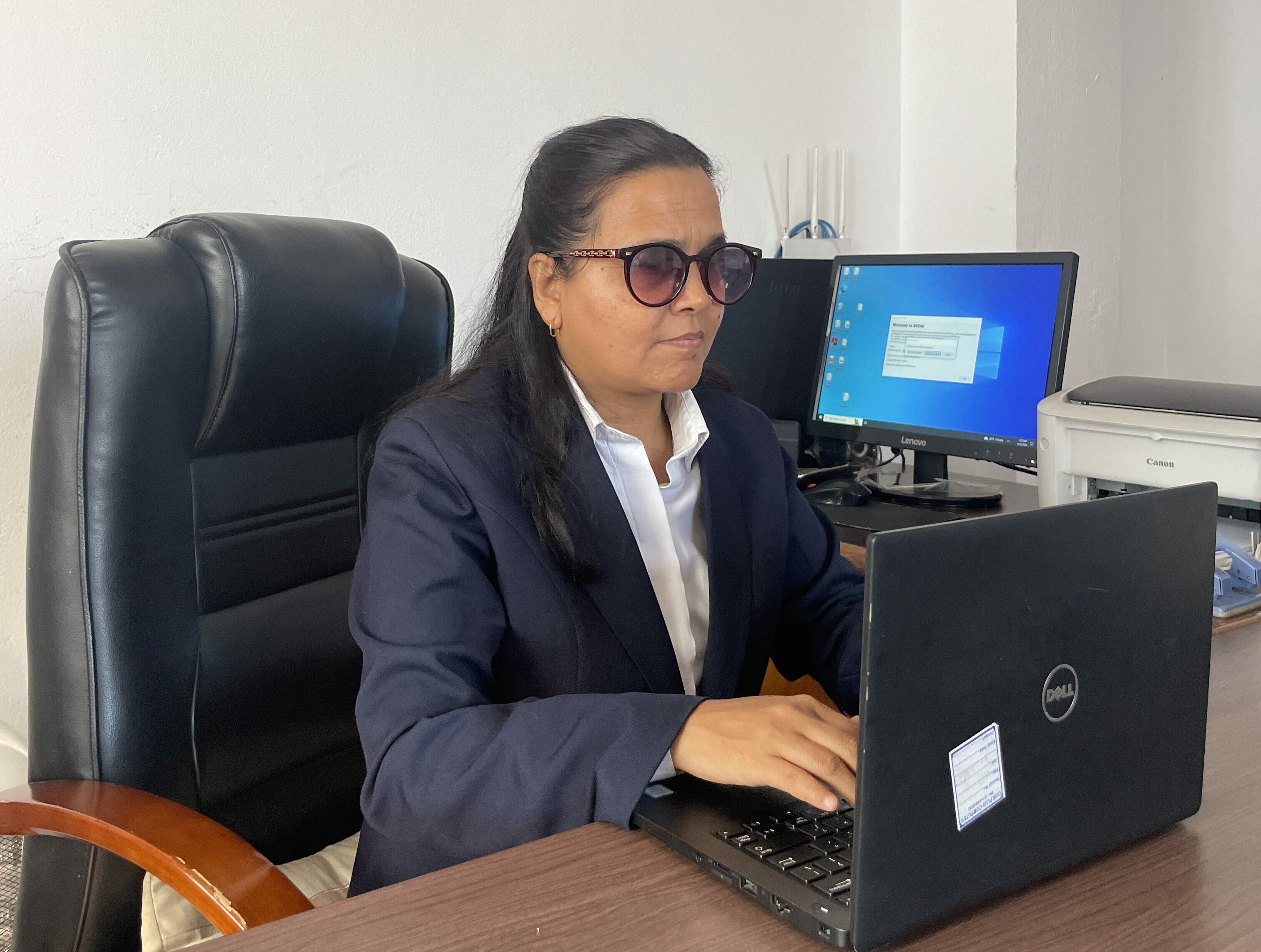 Neera Adhikari types on a computer at her desk.