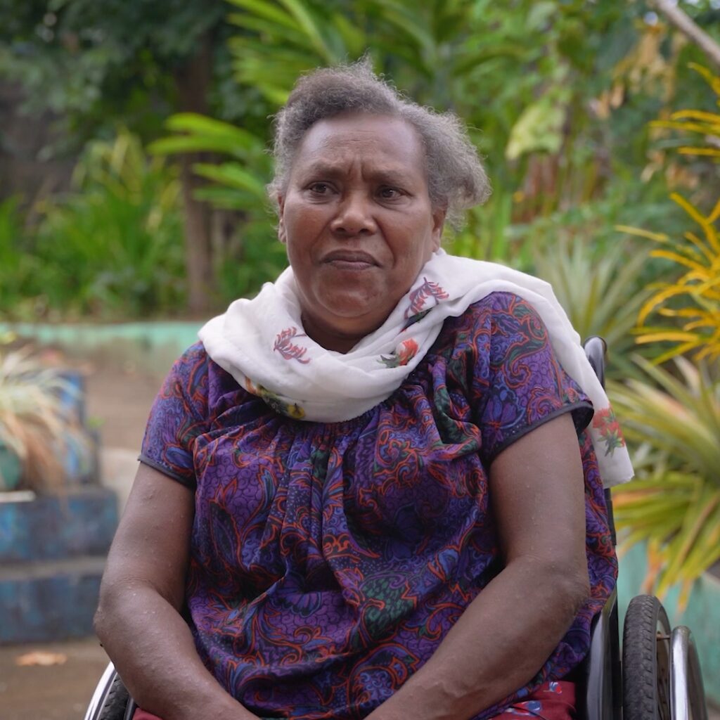 A ni-Vanuatu woman sits outside in a wheelchair.