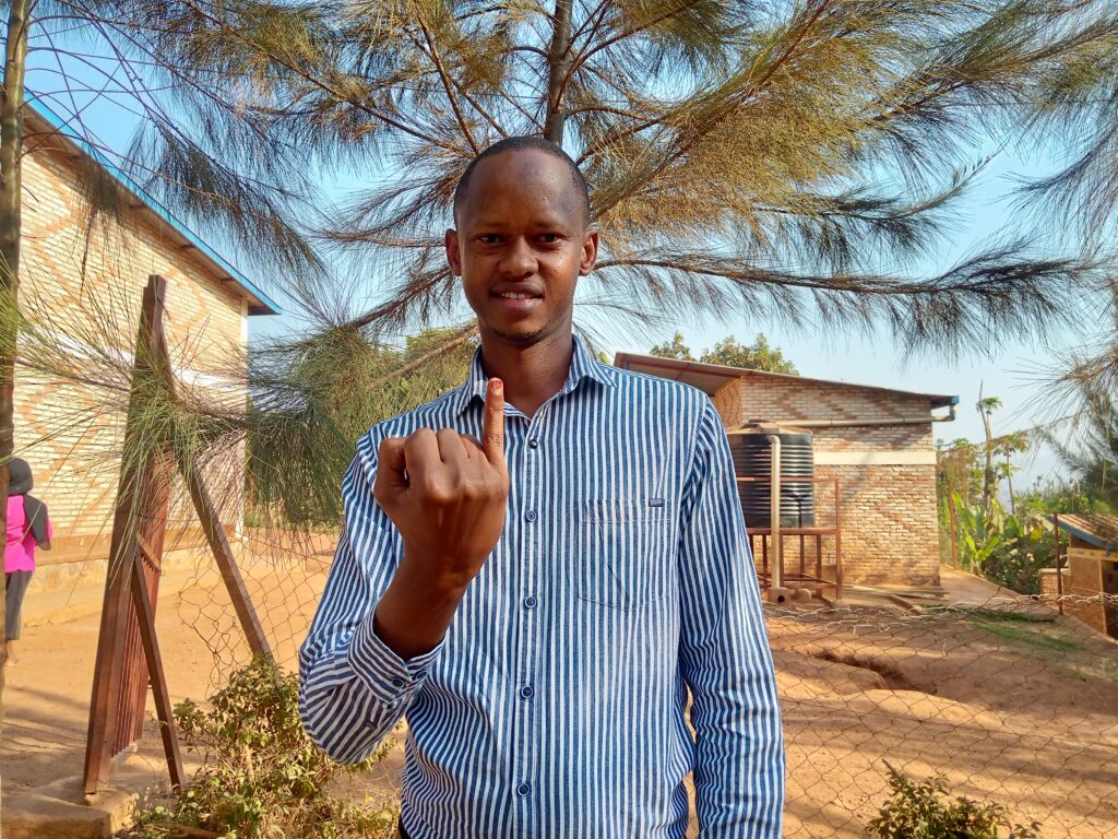 Jean Damascene Bizimana, a Deaf Rwandan man, holds up his -ink-stained pinky finger to show that he's voted.