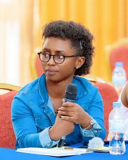 Baslissa Uwishyakas, a young Rwandan woman with dwarfism, holds a microphone at a conference.