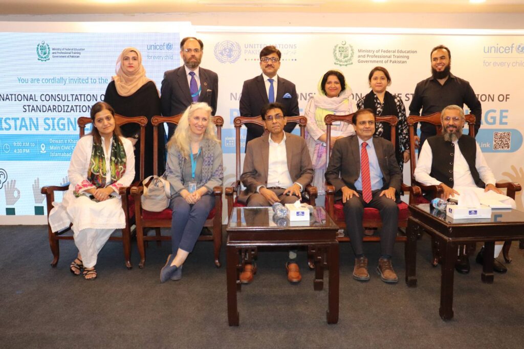 Six leaders stand behind five seated leaders. The men and women are wearing formal attire. A banner sprawling behind them displays the emblems of UNICEF, the United Nations, and the Ministry of Federal Education and Professional Training.