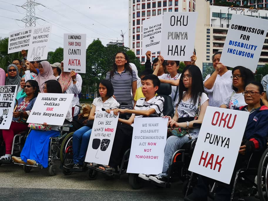 Malaysian activists gather in a circle outside to protest.