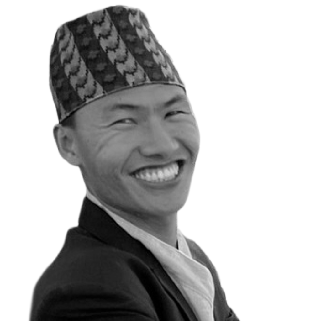 Urgyen Namdul smiles into the camera. He is a young Nepali man wearing a suit and traditional hat.