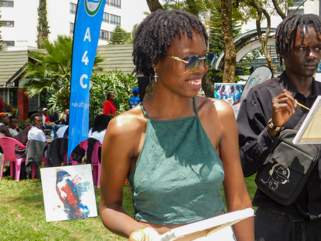 Joan Cherotich smiles while participating in an outdoor art festival.